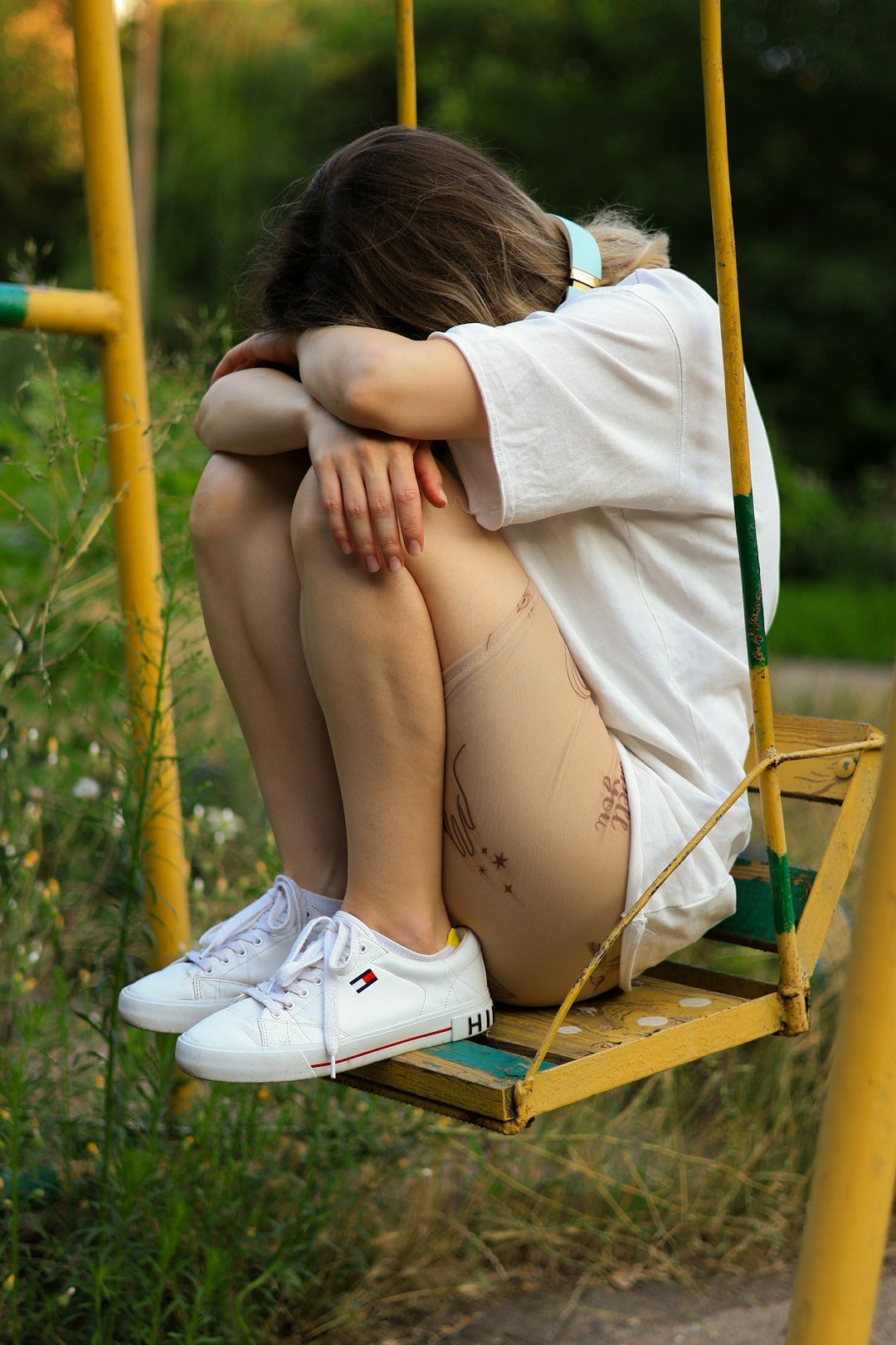 Photo by Anna Keibalo a woman sitting on a swing with her legs crossed