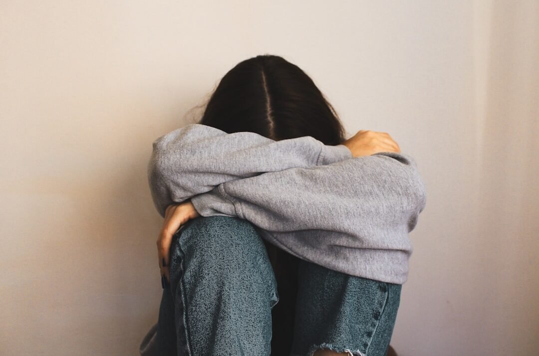 a woman sitting on the floor with her arms wrapped around her head