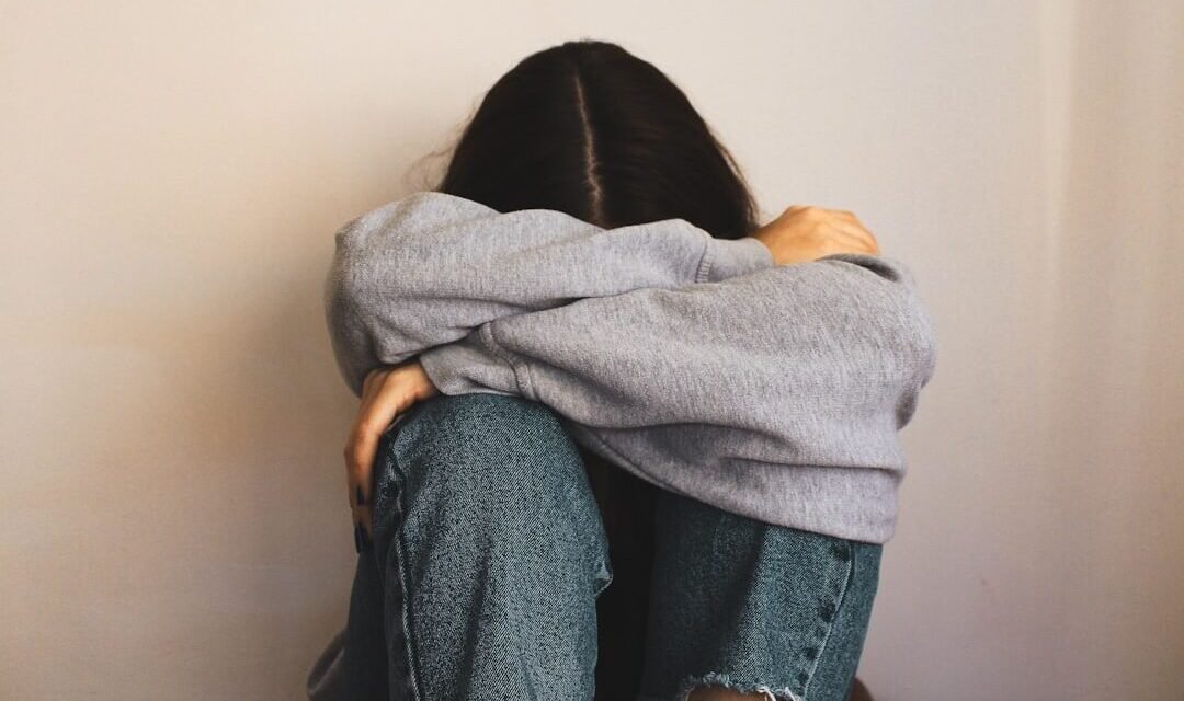 a woman sitting on the floor with her arms wrapped around her head