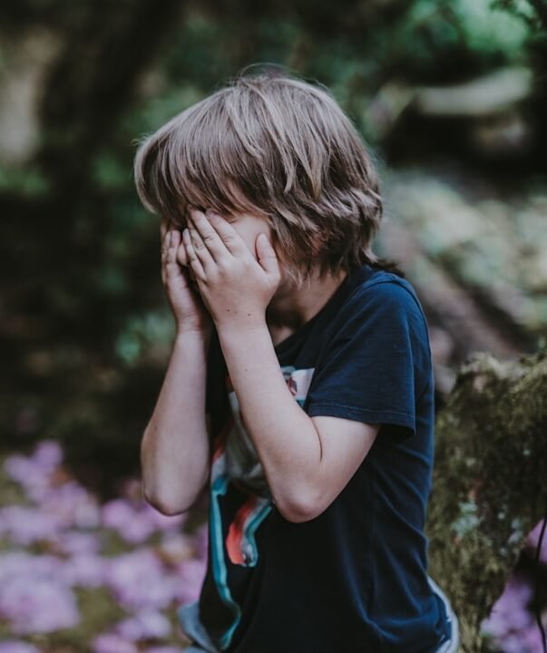 boy covering his face while standing