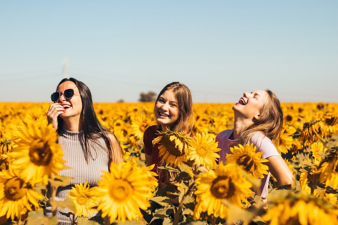 Photo by Antonino Visalli woman in white and black striped shirt standing on yellow sunflower field during daytime