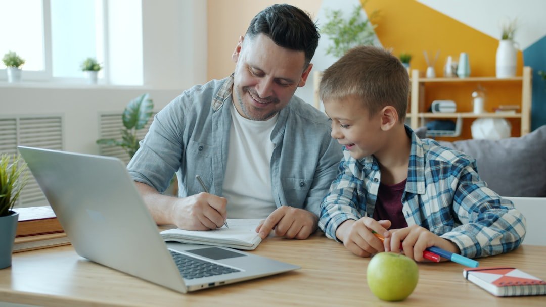 Photo by Vitaly Gariev Father and son studying together at a desk.