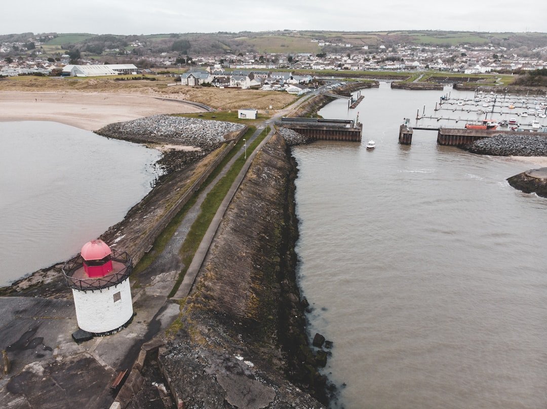 Photo by Matt Seymour a red and white lighthouse sitting on the side of a river
